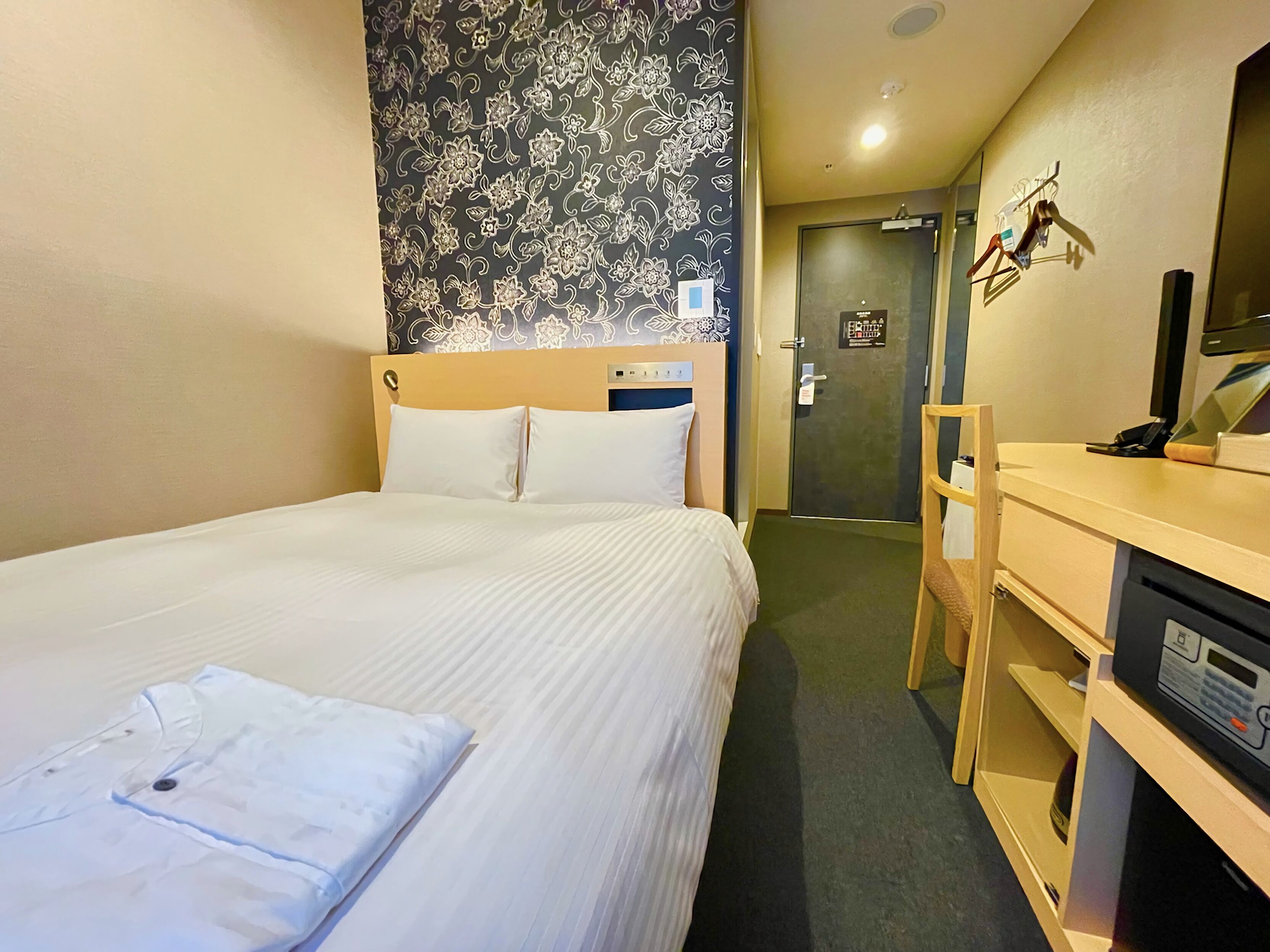 Una habitación de hotel con cama, escritorio y armario.