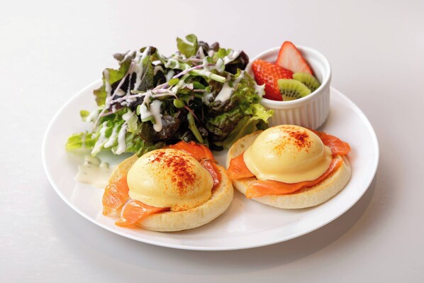 A plate with two eggs benedict sandwiches, a side salad, and a small bowl of fruit. - The Kanzashi Tokyo Asakusa (Tokyo)