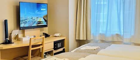 A hotel room with a desk, television, and two beds.