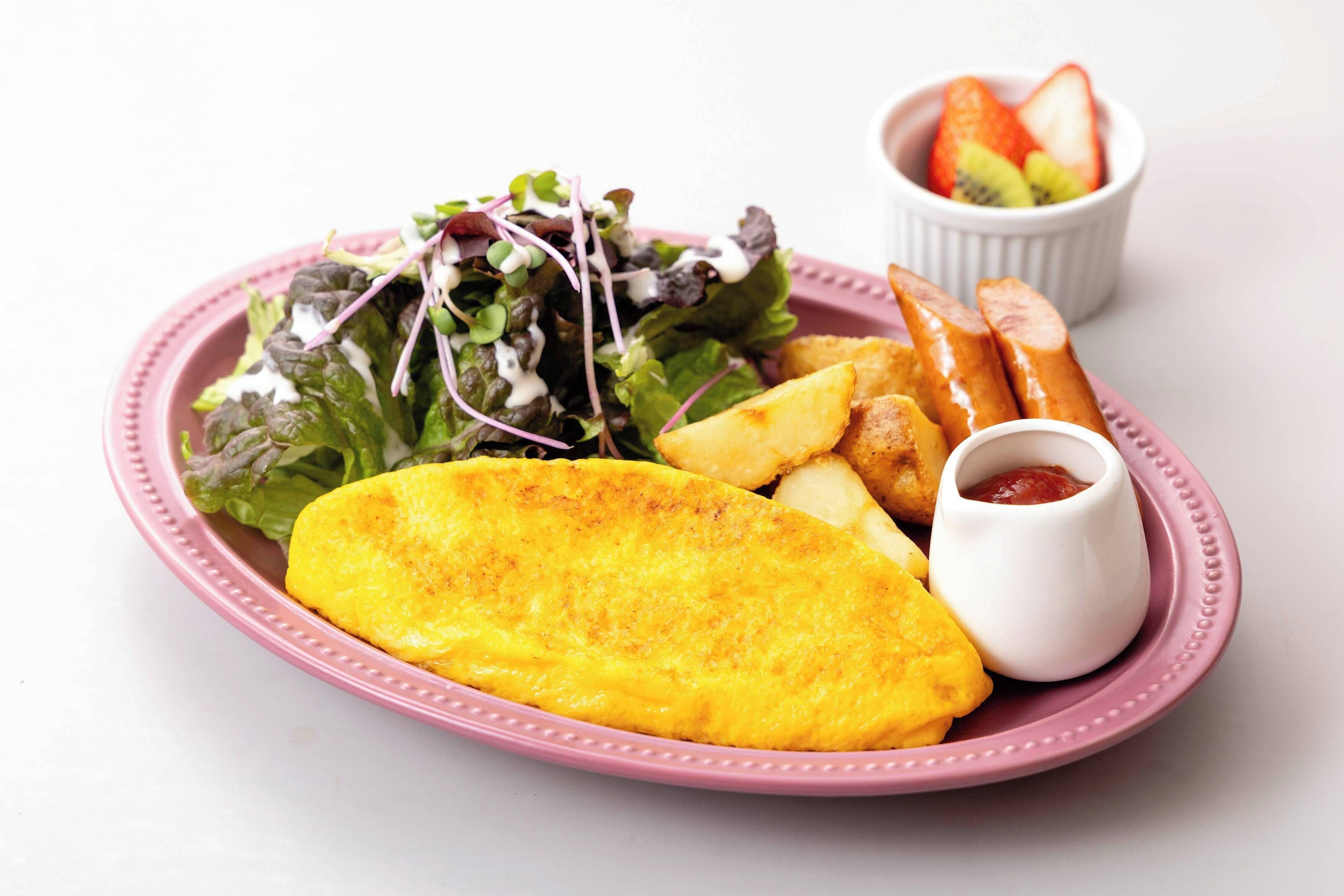 Un plato con un huevo frito, cuñas de patata, una ensalada y un recipiente pequeño con kétchup.