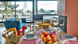 Un coin repas avec une table dressée pour quatre personnes, un canapé bleu et une vue sur l’extérieur.