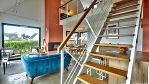 Un intérieur moderne avec un canapé bleu, un escalier en bois et un coin repas.