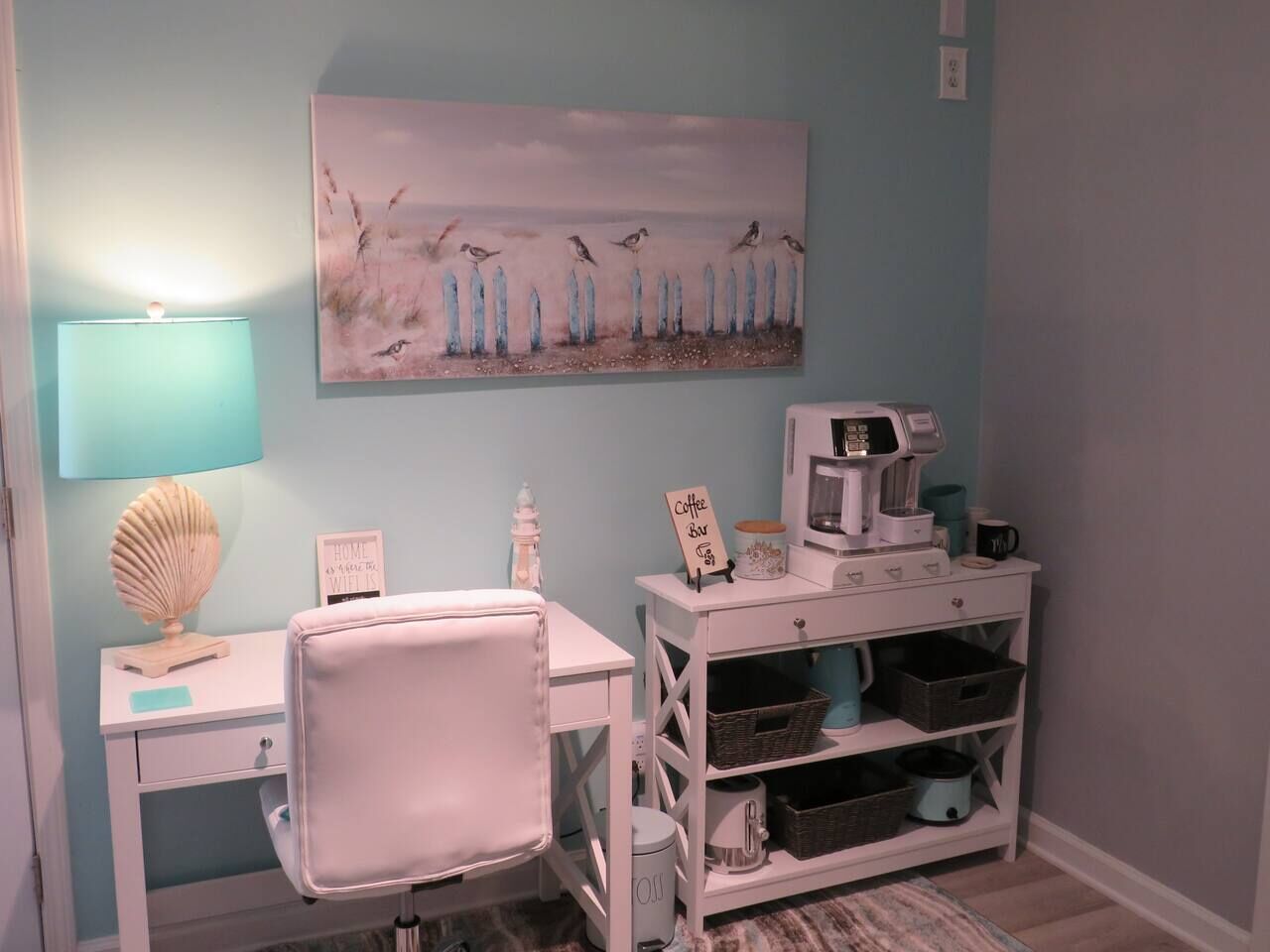 A small, neatly organized room with a desk, chair, coffee machine, and storage shelves.