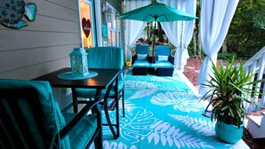 A patio with a table and chairs, a lantern, and a potted plant. - Suite Paradise: Queen Suite Near Beach, Golf Cart, Hot Tub (Emerald Isle)