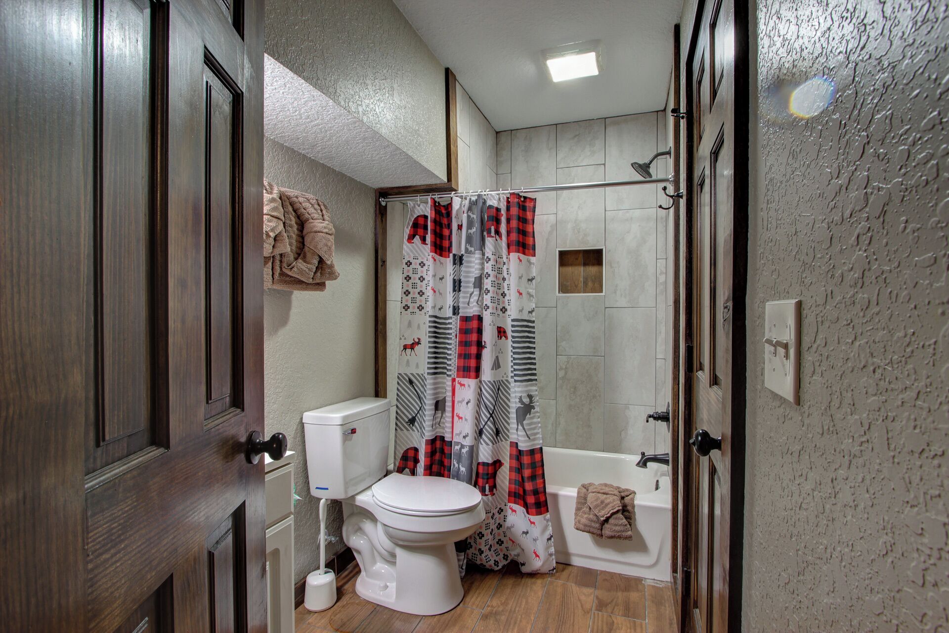A bathroom with a toilet, shower curtain, and a towel hanging on the wall.