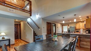 A spacious kitchen with a wooden table and chairs, a built-in oven, and a refrigerator. - Easy Access • No Steep Roads • Near Parkway • Hot Tub • Arcade • 3 Master Suites (Pigeon Forge)