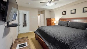 A bedroom with a bed, a ceiling fan, a TV mounted on the wall, and a dresser. - Ground Floor Beachfront Suite - Sleeps 4 - Pool and Sauna (Lincoln City)