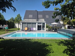 A swimming pool with lounge chairs and a covered patio area.