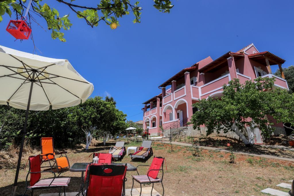 A building with a red facade and white trim, outdoor seating with red and white chairs, and a large white umbrella.