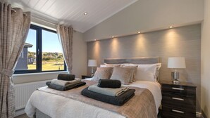 A modern bedroom with a large bed, two bedside tables, and a view of the outdoors.