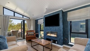 A modern living room with a fireplace, comfortable seating, and large windows.