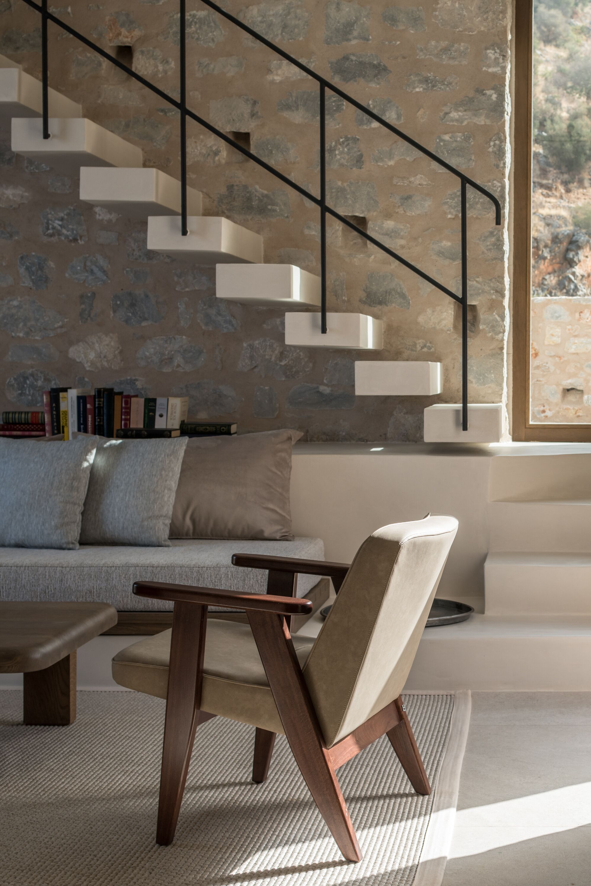 A modern living room with a staircase, a sofa, and a chair.