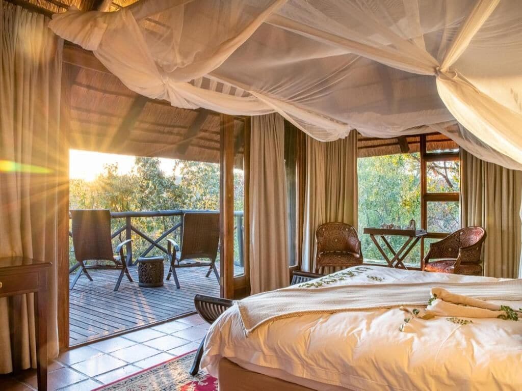 Een slaapkamer met een bed, een houten terras en een tafel met stoelen.