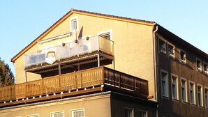 Un bâtiment doté d’un balcon et d’un foyer au premier plan.