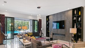 Un salon moderne doté d’un grand téléviseur, de sièges confortables et d’une cheminée.