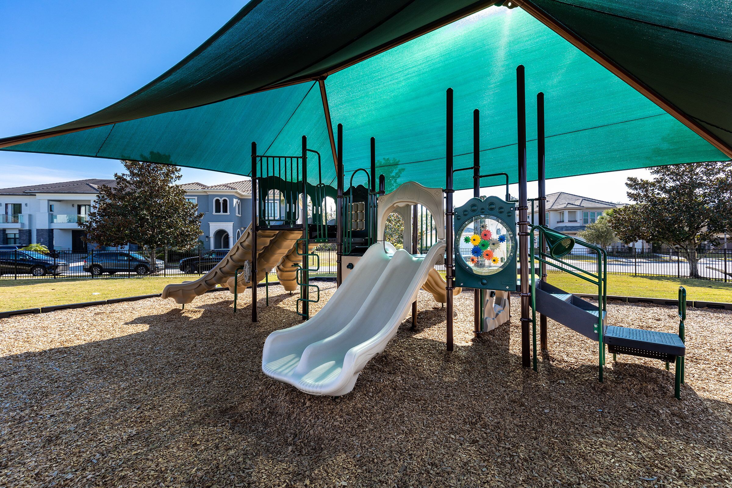 A playground with a slide, climbing structures, and a shaded area.