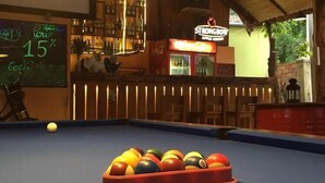 A pool table with a chalkboard sign advertising a 15% discount on cocktails. - Langchia Hostel & Bar (Phu Quoc)