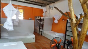 A dormitory room with bunk beds, a fan, and a tree decoration. - Langchia Hostel & Bar (Phu Quoc)