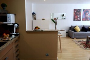 A compact living space with a kitchenette, a grey sofa, and a small dining area. - APARTMENTS BCN CENTRAL-MONTJUIC (Barcelona)