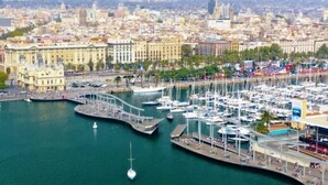 Un port de plaisance avec des bateaux, un grand bâtiment à colonnes et une vue sur la ville en arrière-plan.