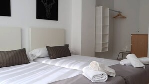Une chambre d’hôtel comprenant un lit, des oreillers, une serviette, un porte-manteau et une armoire.