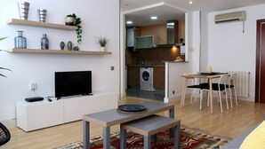 Un appartement moderne équipé d’une télévision, d’un coin repas, d’une cuisine et d’un lave-linge.