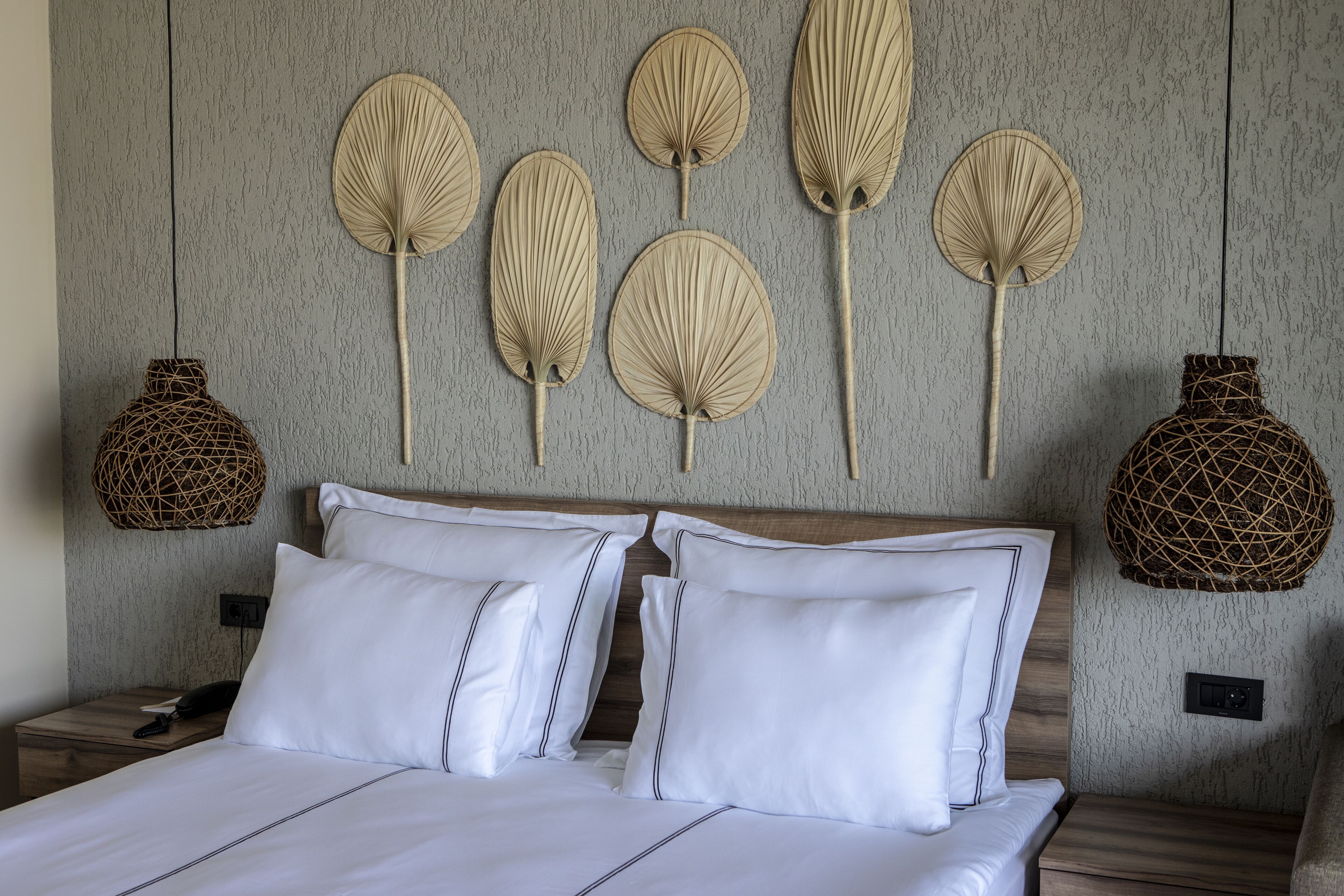 Una cama bien tendida con sábanas y almohadas blancas, un cabecero de madera y adornos decorativos en la pared.