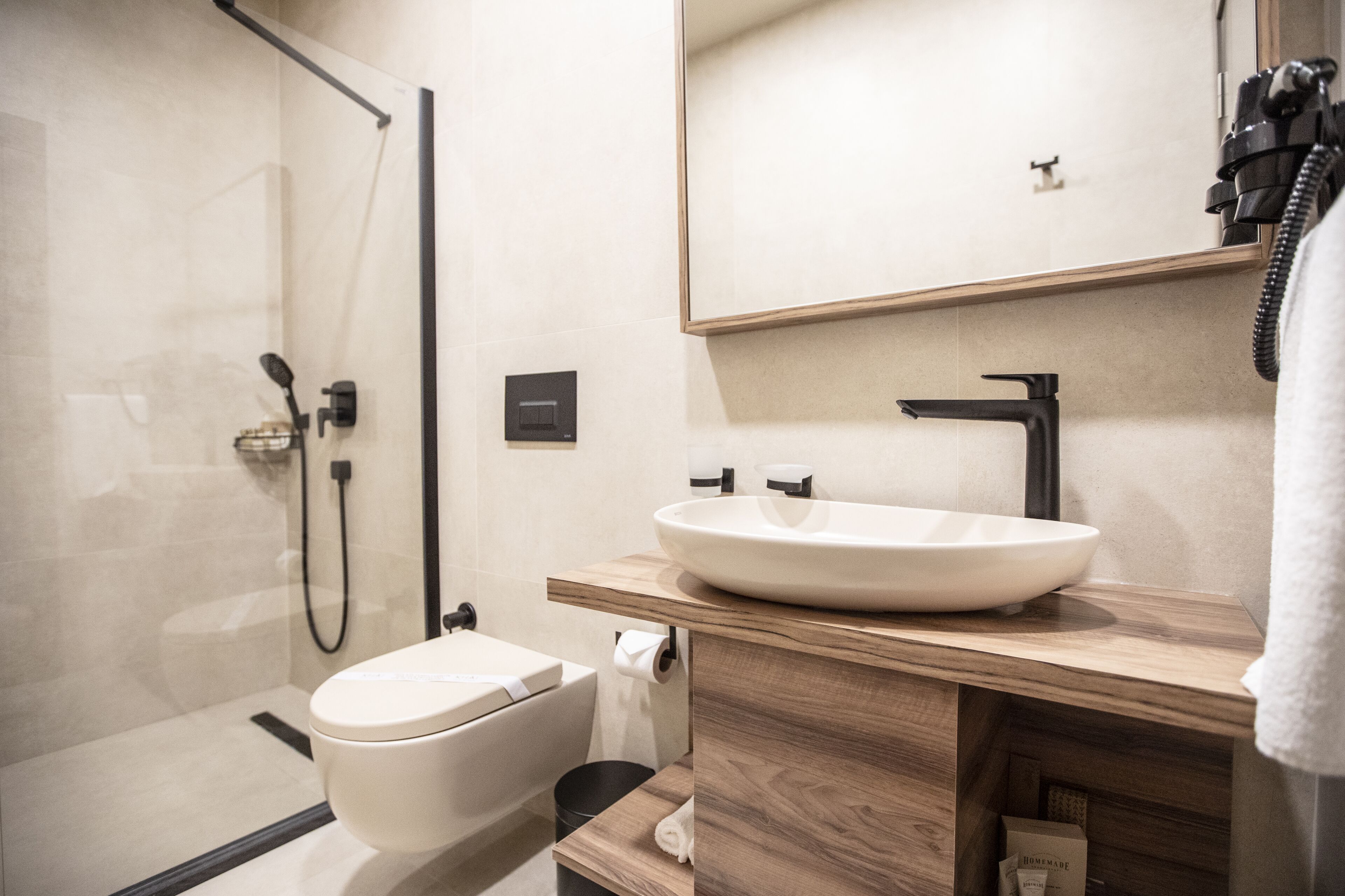 A modern bathroom with a glass-enclosed shower, a white sink, and a wooden vanity.