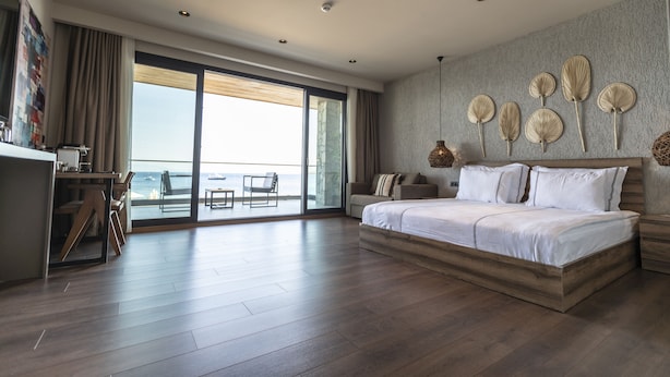A modern hotel room with a large bed, a desk, and a balcony with a view of the sea. - Khai Hotel Bodrum (Bodrum)
