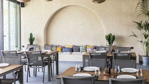 A restaurant with tables set for dining, a large arched wall, and hanging wicker lamps. - Khai Hotel Bodrum (Bodrum)