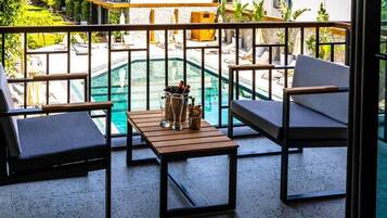 Ein Balkon mit Pool, Liegestühlen und einem Tisch mit Getränkekaraffe.