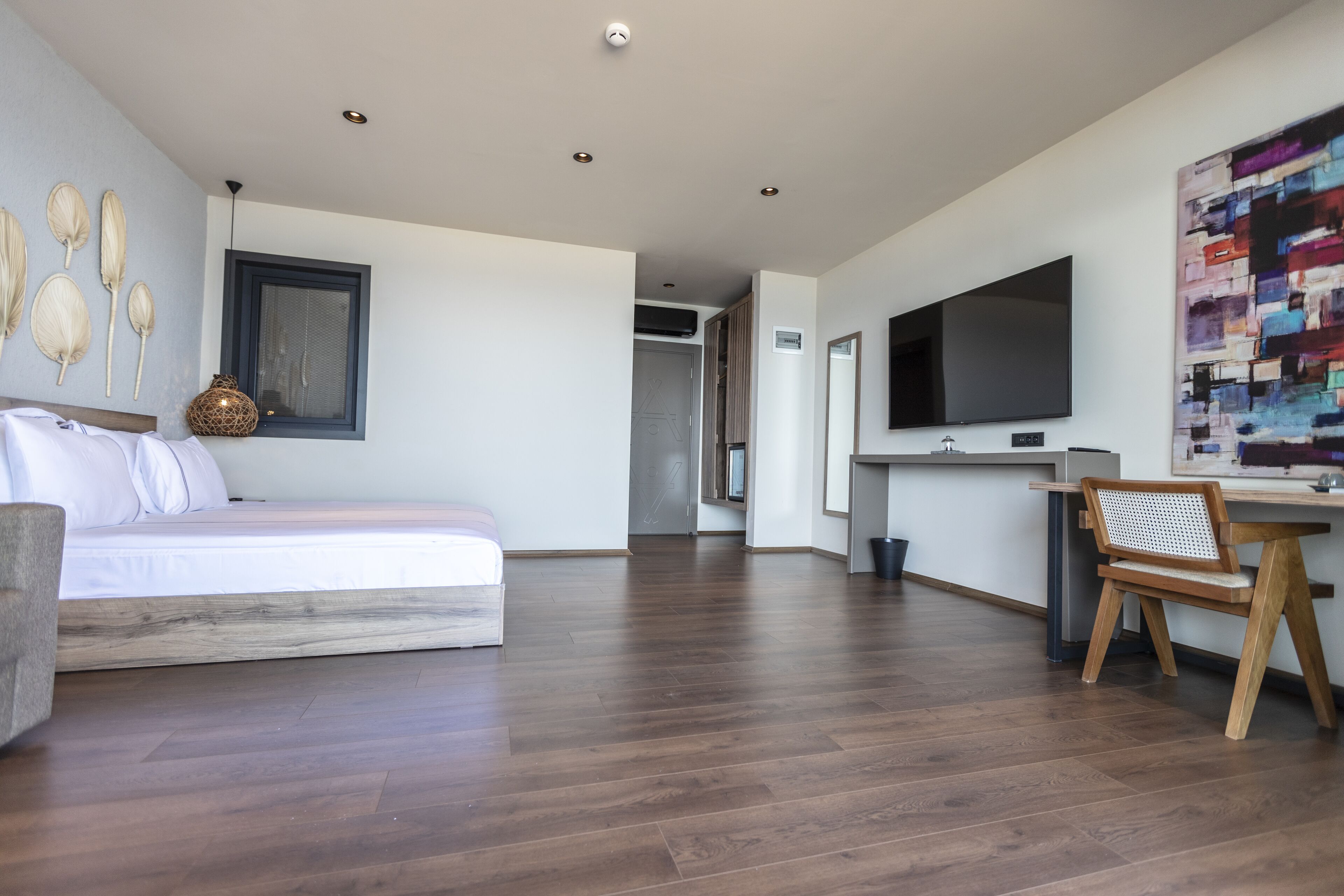 A modern bedroom with a bed, a desk, and a TV.