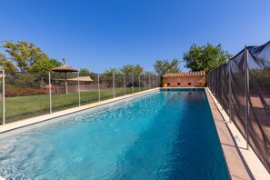 A rectangular swimming pool with a clear blue water surface, surrounded by a fence and a grassy area with a small pavilion. - Parra familiy friendly Country House in the Picturesque Southeast of Majorca (Santanyí)
