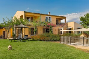 A yellow villa with a balcony, a thatched roof, and a fenced garden. - Parra familiy friendly Country House in the Picturesque Southeast of Majorca (Santanyí)