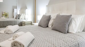 Quarto de hotel com cama grande, mesa de cabeceira, espelho e um quadro na parede.