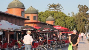 Een binnentuin met buiten zitplaatsen, rode parasols en bakstenen gebouwen met koepeldaken.