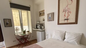 Een hotelkamer met een bed, een bureau en een stoel. Er liggen handdoeken op het bed en er hangt een schilderij aan de muur.