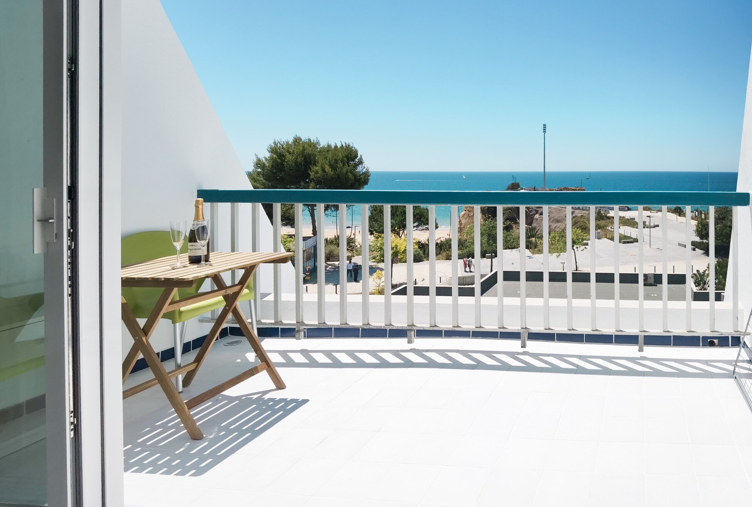 Ein Balkon mit Meerblick, ein Tisch, ein Stuhl und eine Champagnerflasche.