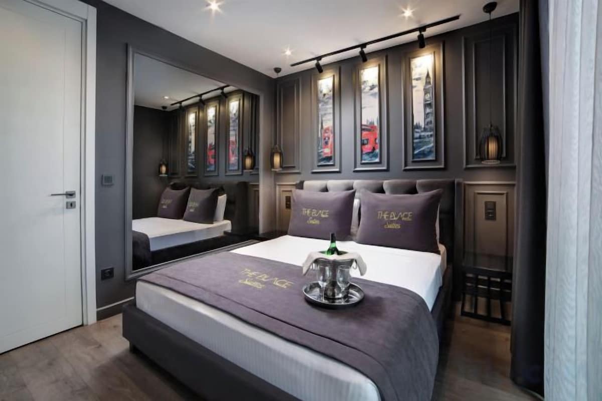 A modern bedroom with a large bed, a bedside table, and a mirror.