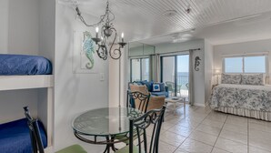 Ein Zimmer mit Etagenbetten, einem Glastisch und einem Balkon mit Blick.
