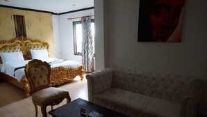 Quarto de hotel com cama grande, sofá, mesa de centro e um quadro na parede.
