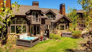 A large house with a hot tub, a deck, and a well-maintained lawn.