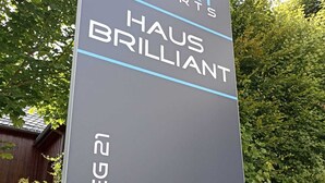 Une enseigne indiquant « Smart Resorts Haus Brilliant », avec l’inscription « BUCHENWEG 21 ».