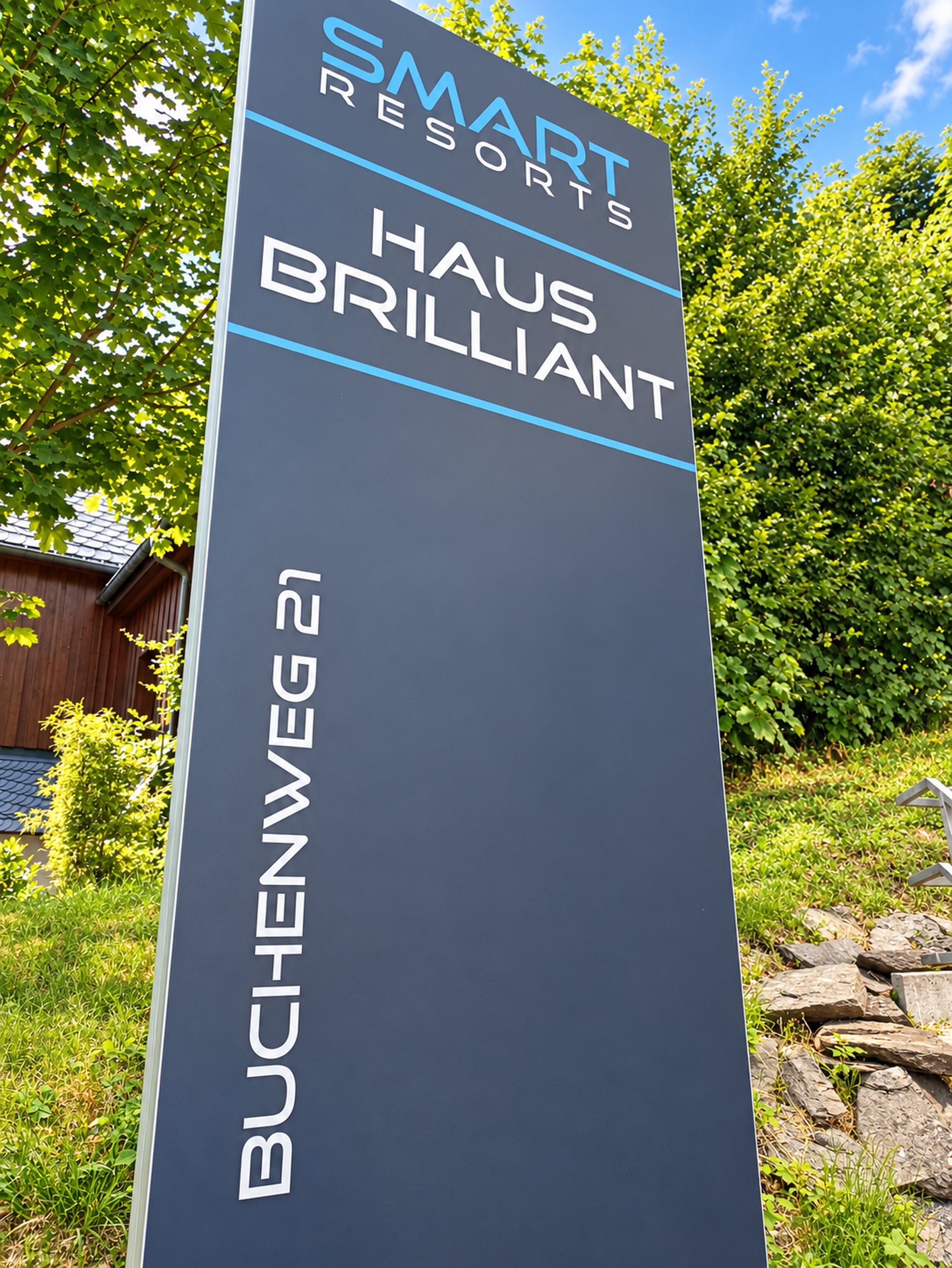 En skylt för Smart Resorts Haus Brilliant, med adressen Buchenweg 21.