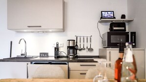 Une cuisine moderne équipée d’une machine à café, d’un four à micro-ondes et d’un coin thé.