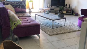 Una sala de estar con un sofá, una mesa de centro, un televisor y una planta en maceta.