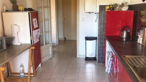 Una cocina con refrigerador, estufa y lavadero. Hay una puerta que conduce a otra habitación.