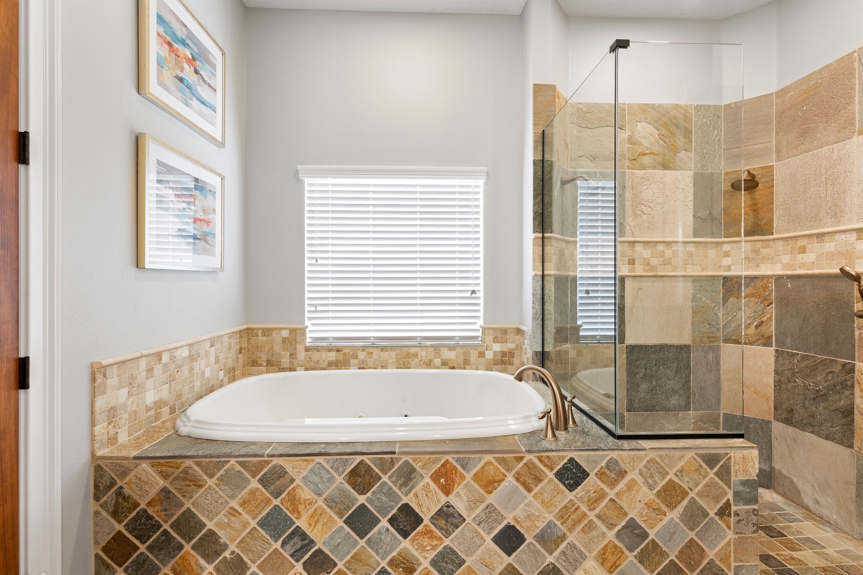 A bathroom with a freestanding bathtub, a glass-enclosed shower, and a tiled floor.