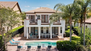 Ein zweistöckiges Haus mit Balkon, Schwimmbad und Terrassenbereich.