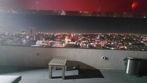 Terraza en la azotea con vista a un paisaje urbano nocturno.